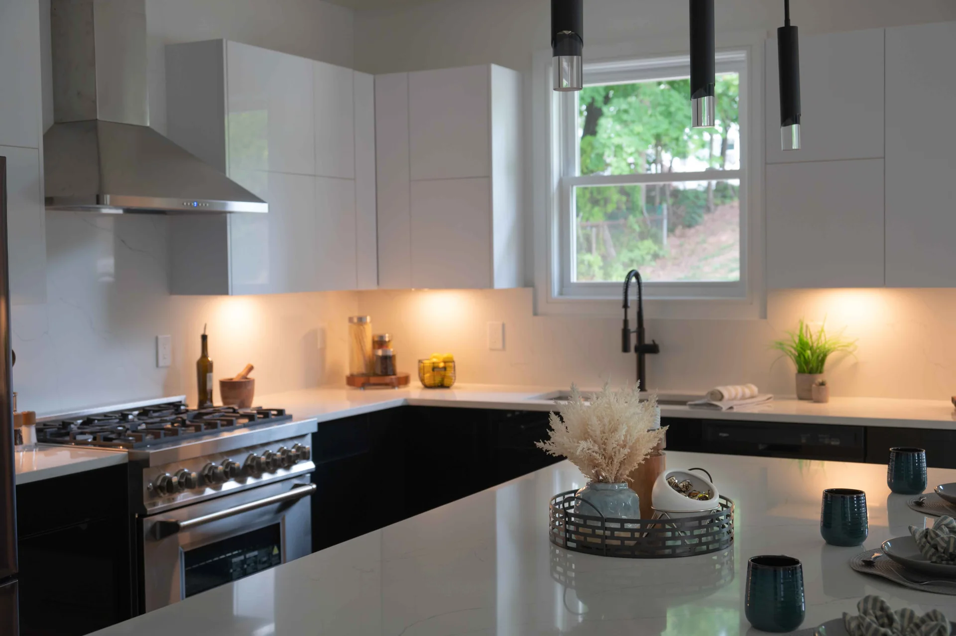 Black base cabinets beneath the range and sink in the white kitchen